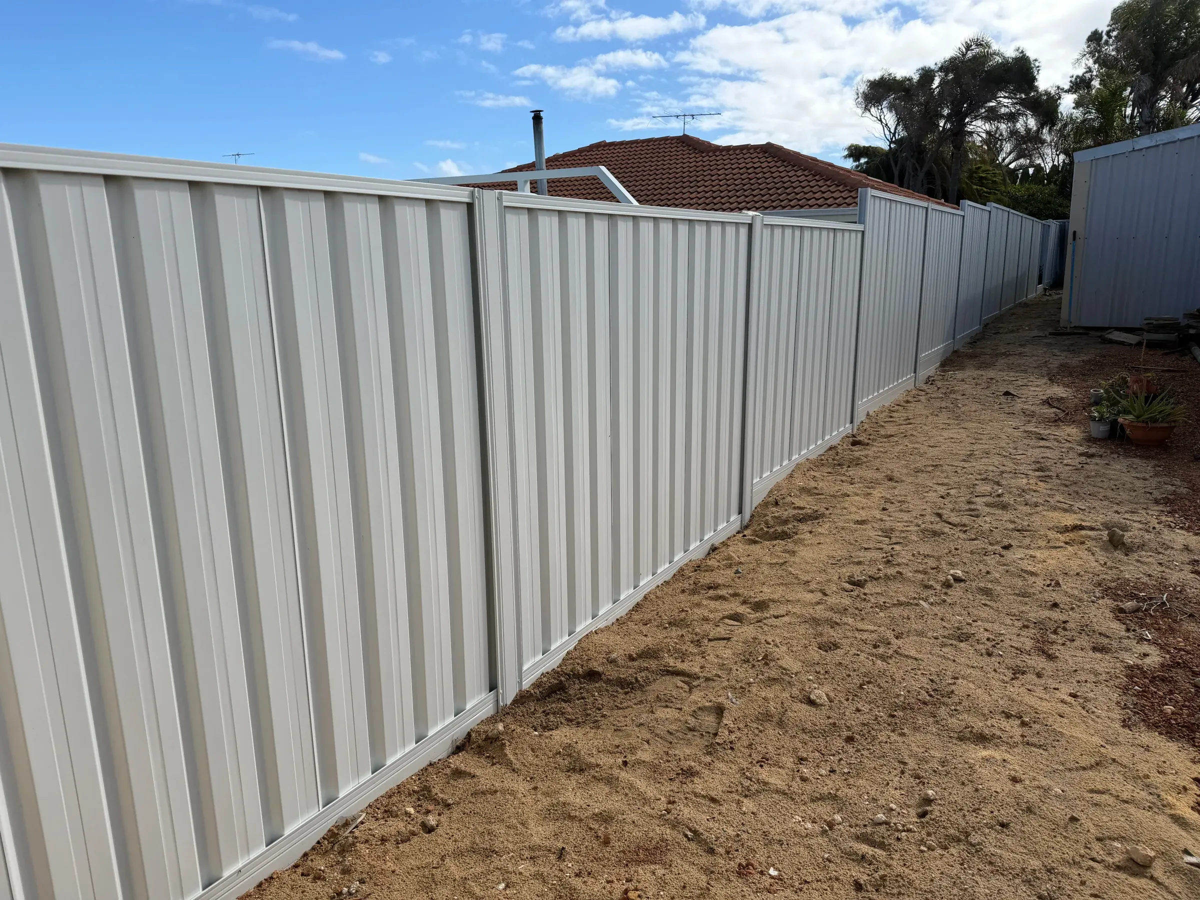 Newly installed cream Colorbond fence on a side boundary before the yard is landscaped