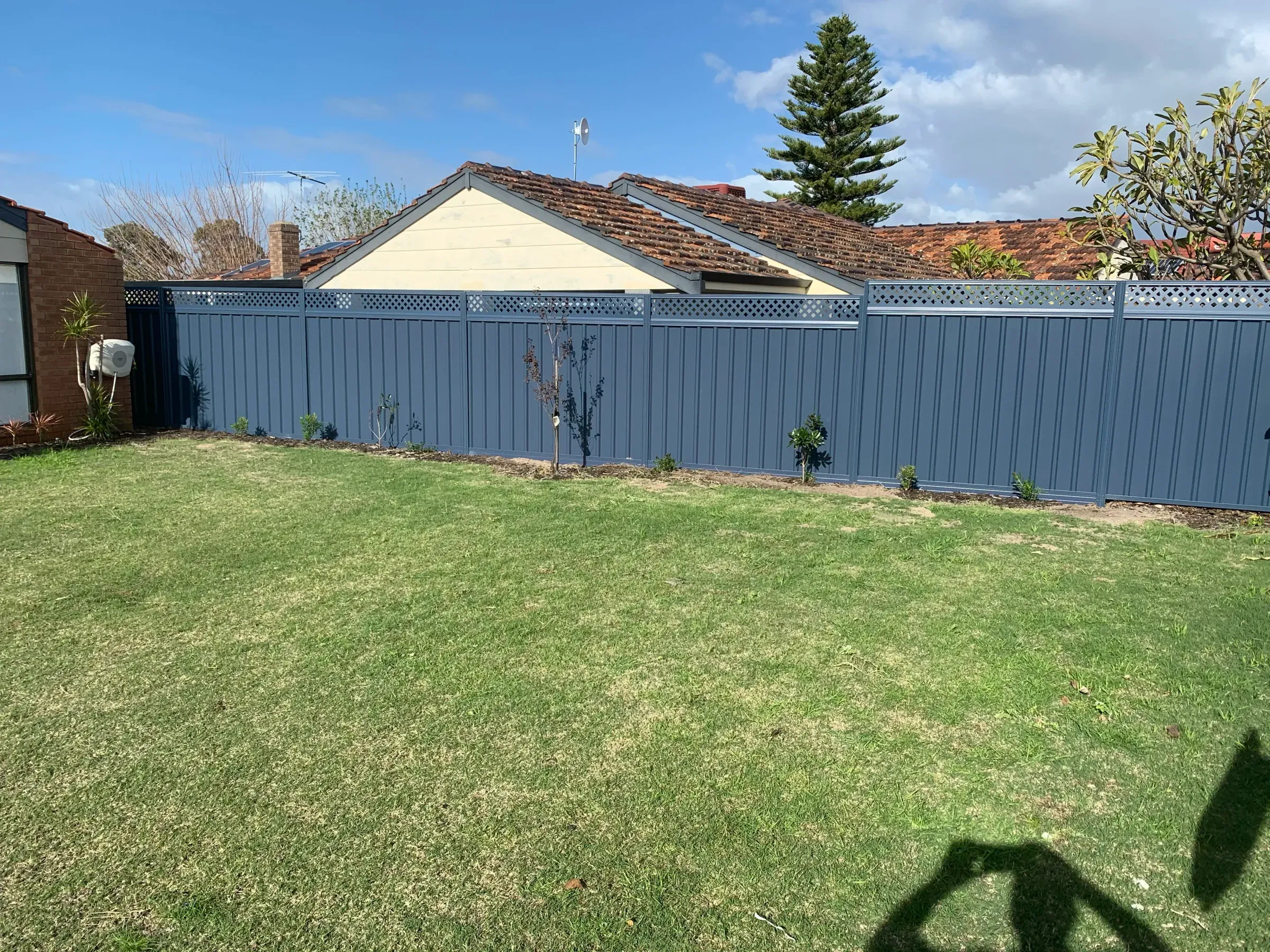 Grey Colorbond fence running the full rear boundary of a lawned backyard