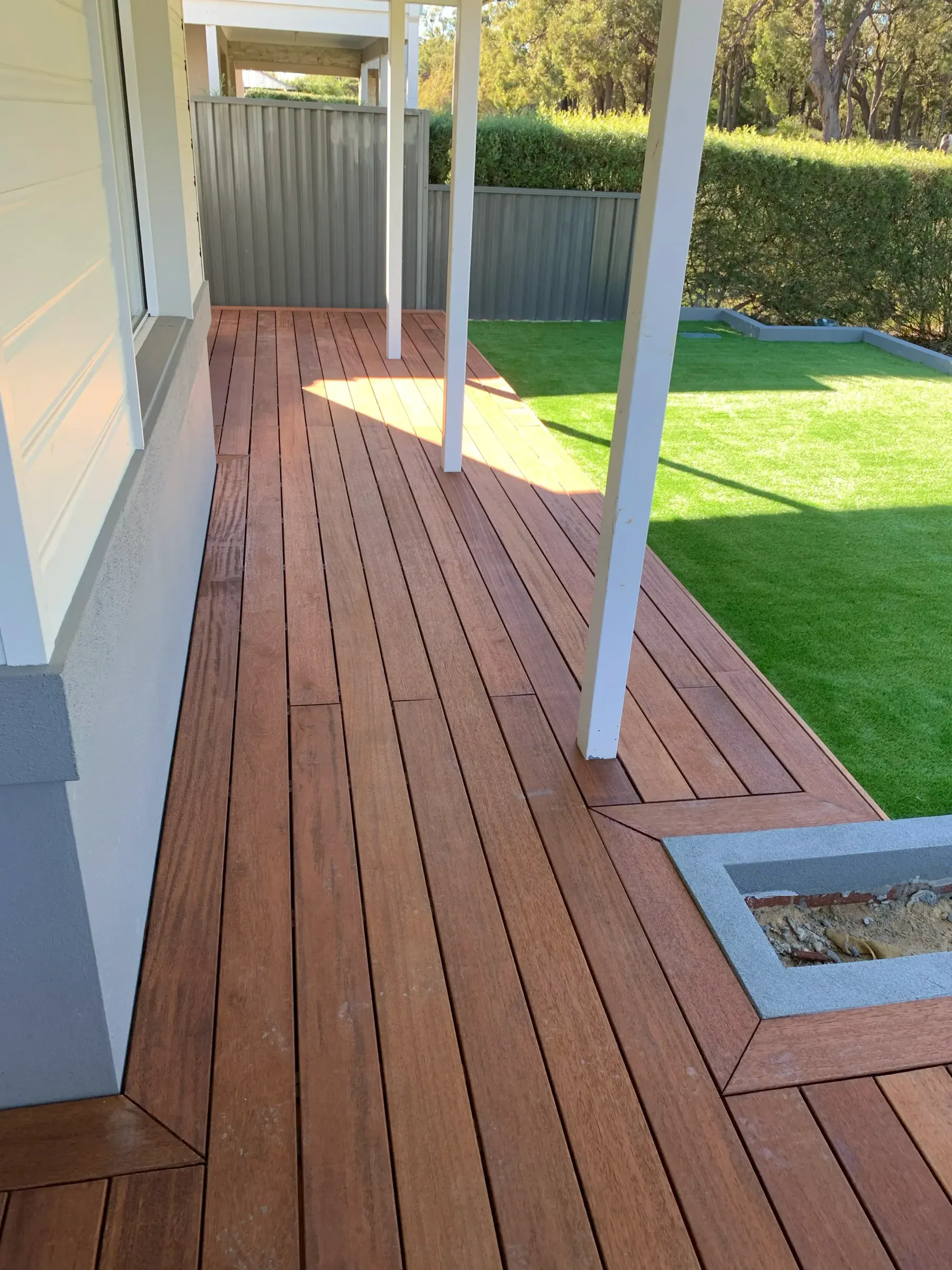 Jarrah deck laid around the posts of a rear alfresco, seen along the boards