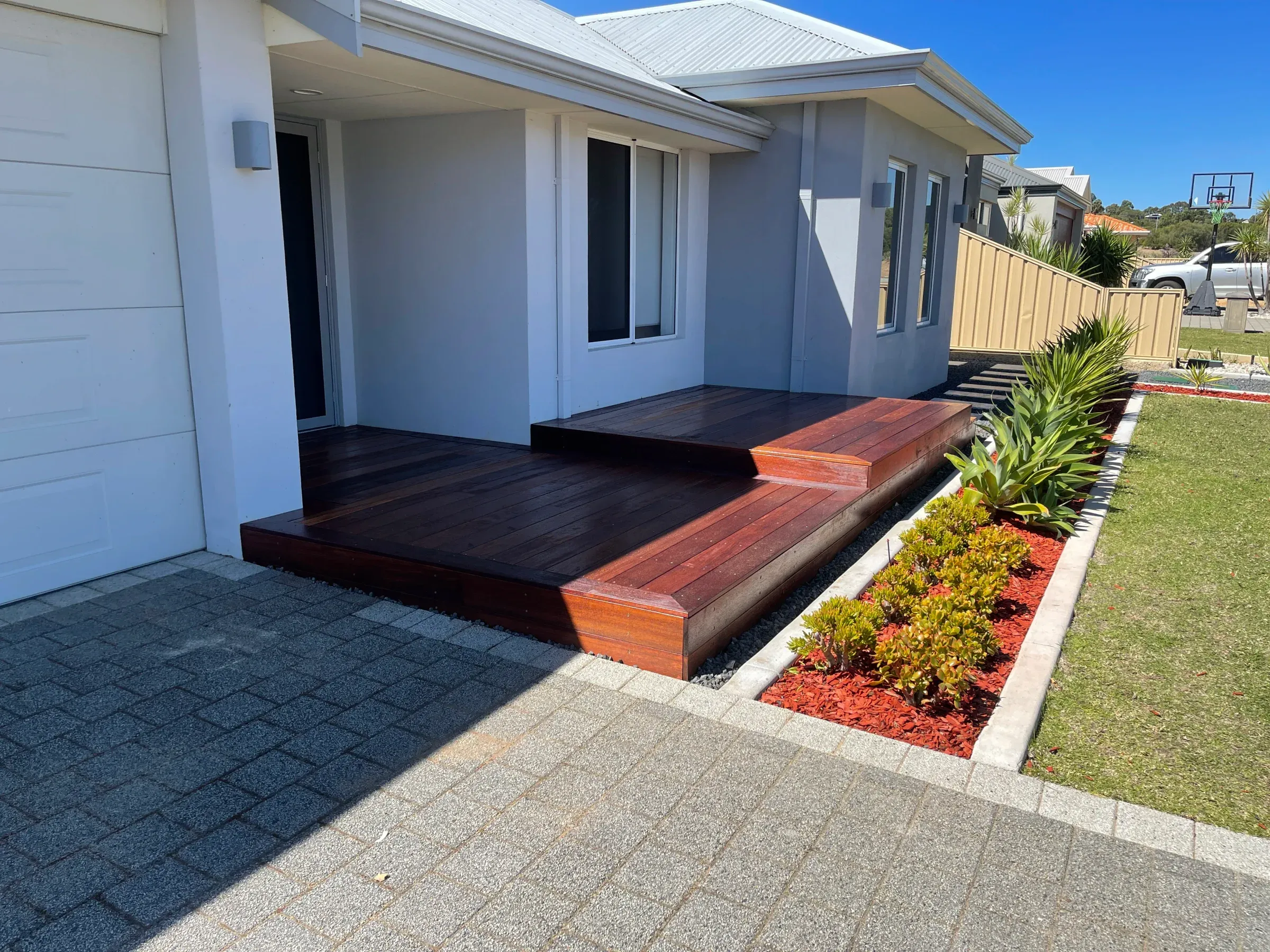 Jarrah entry landing and step set into a garden bed beside a paved path