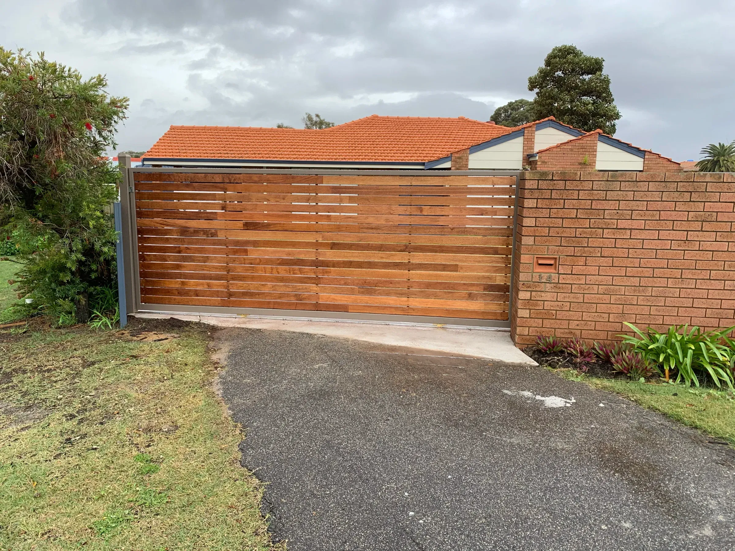 Timber slat double gate standing open onto a gravel driveway