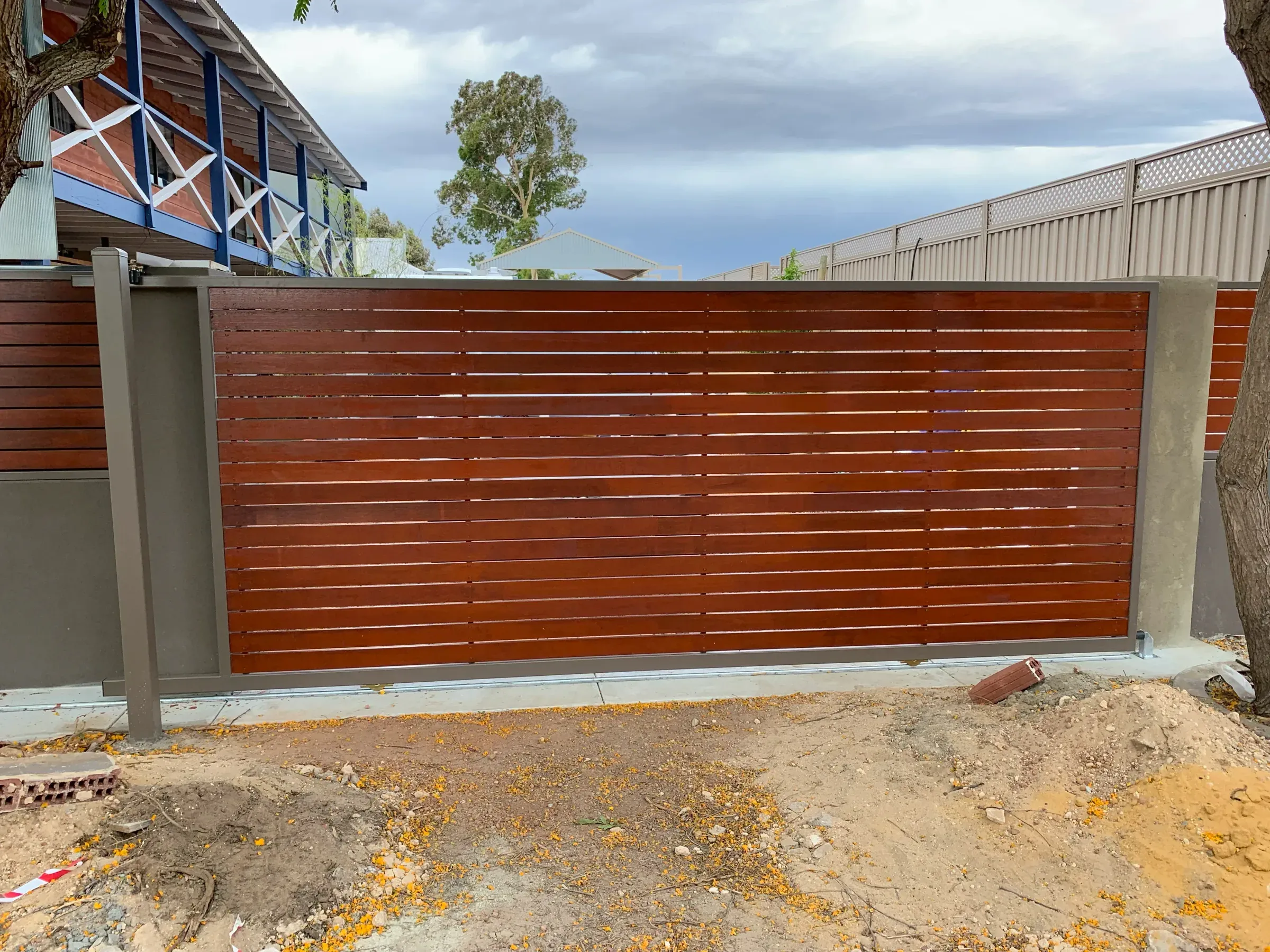Timber slat sliding gate on its track across a driveway entrance