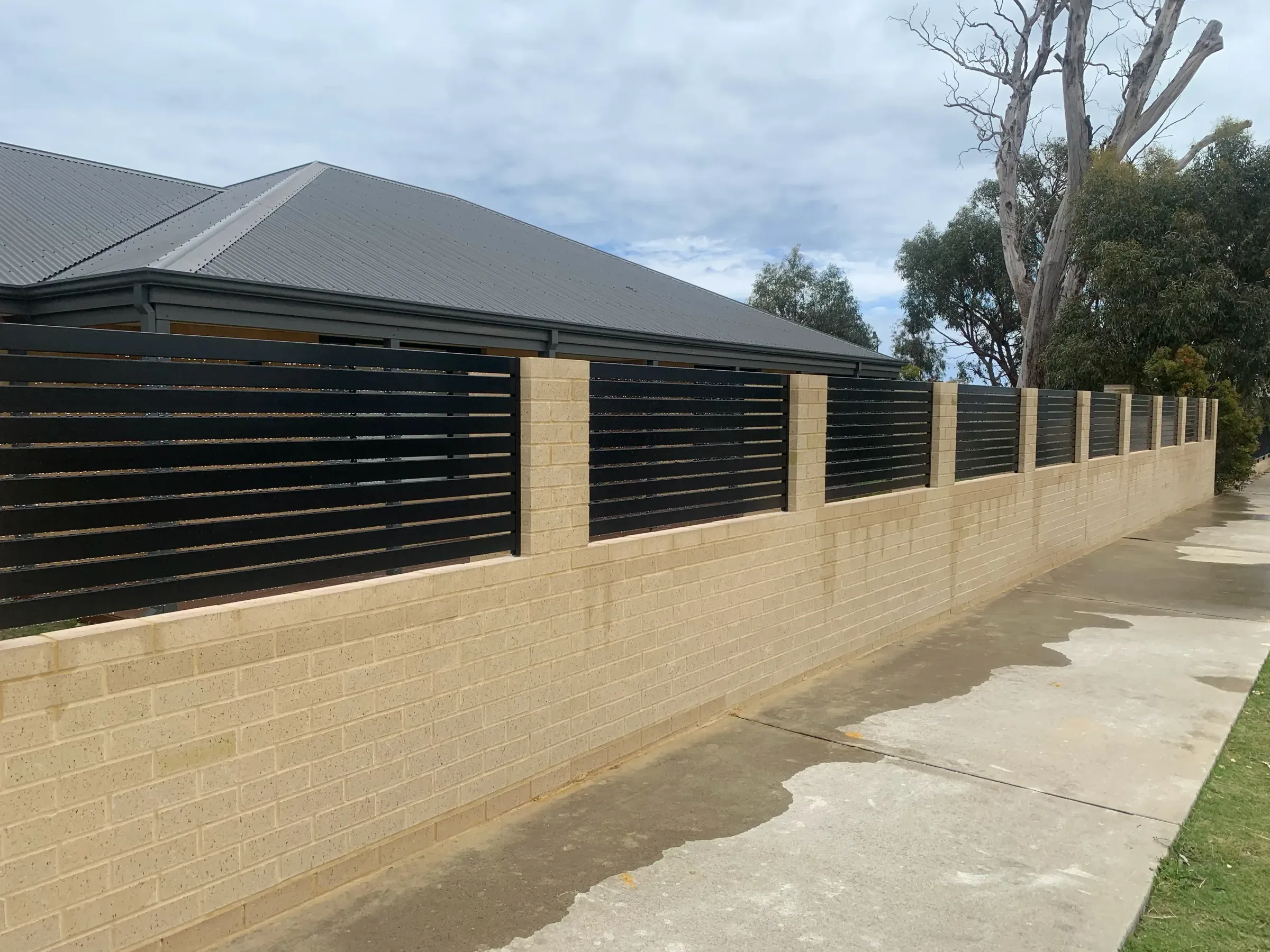Limestone block wall with slat panels running the length of a boundary beside a path