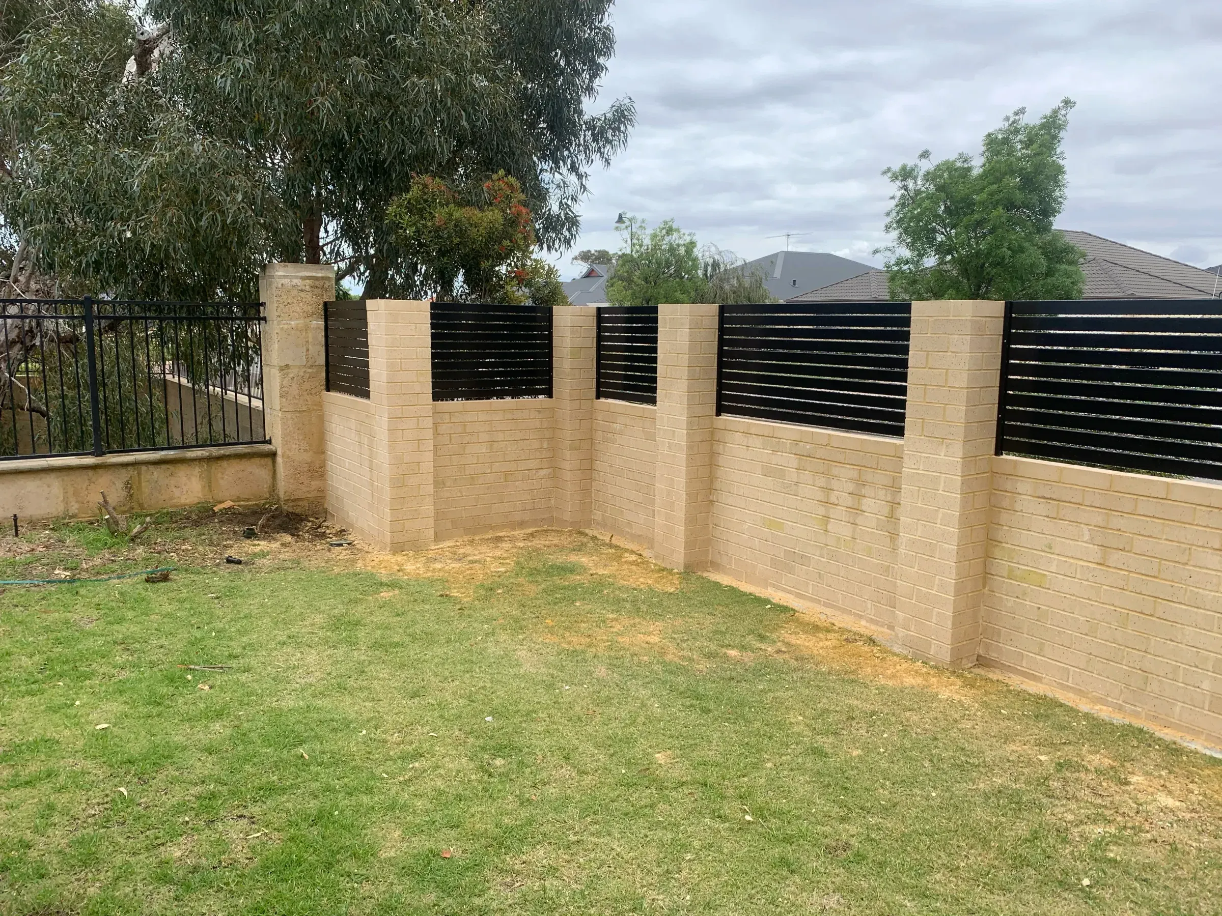 Limestone block wall stepping down a falling boundary with slat panels above