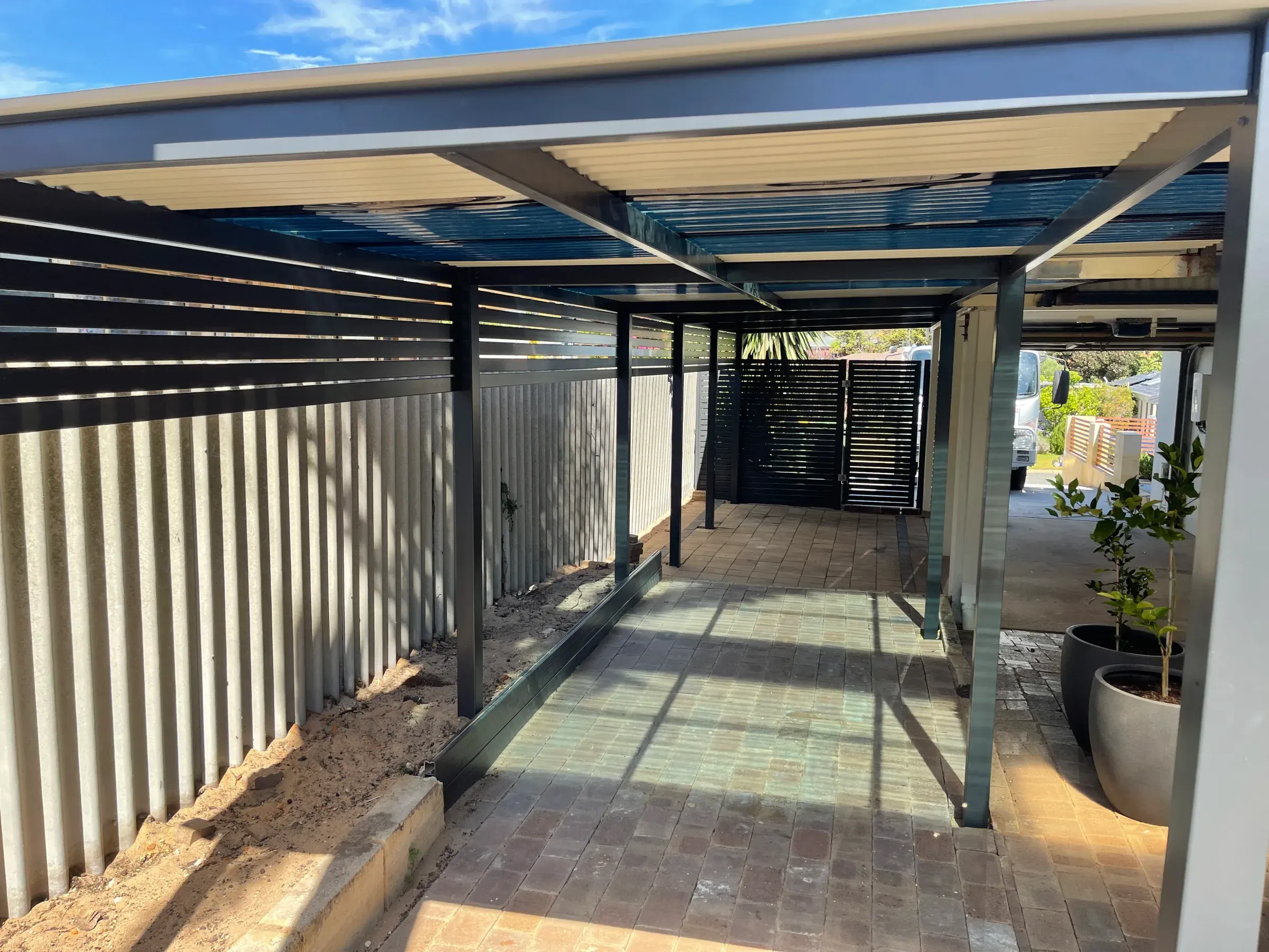 Flat-roof patio covering a paved walkway along the side of a house