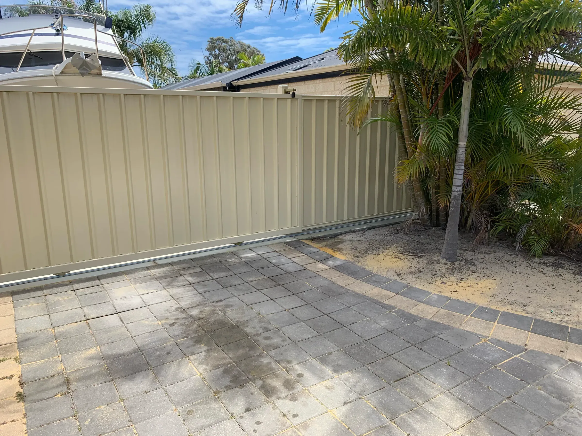 Paved driveway running beside a Colorbond boundary fence to a carport