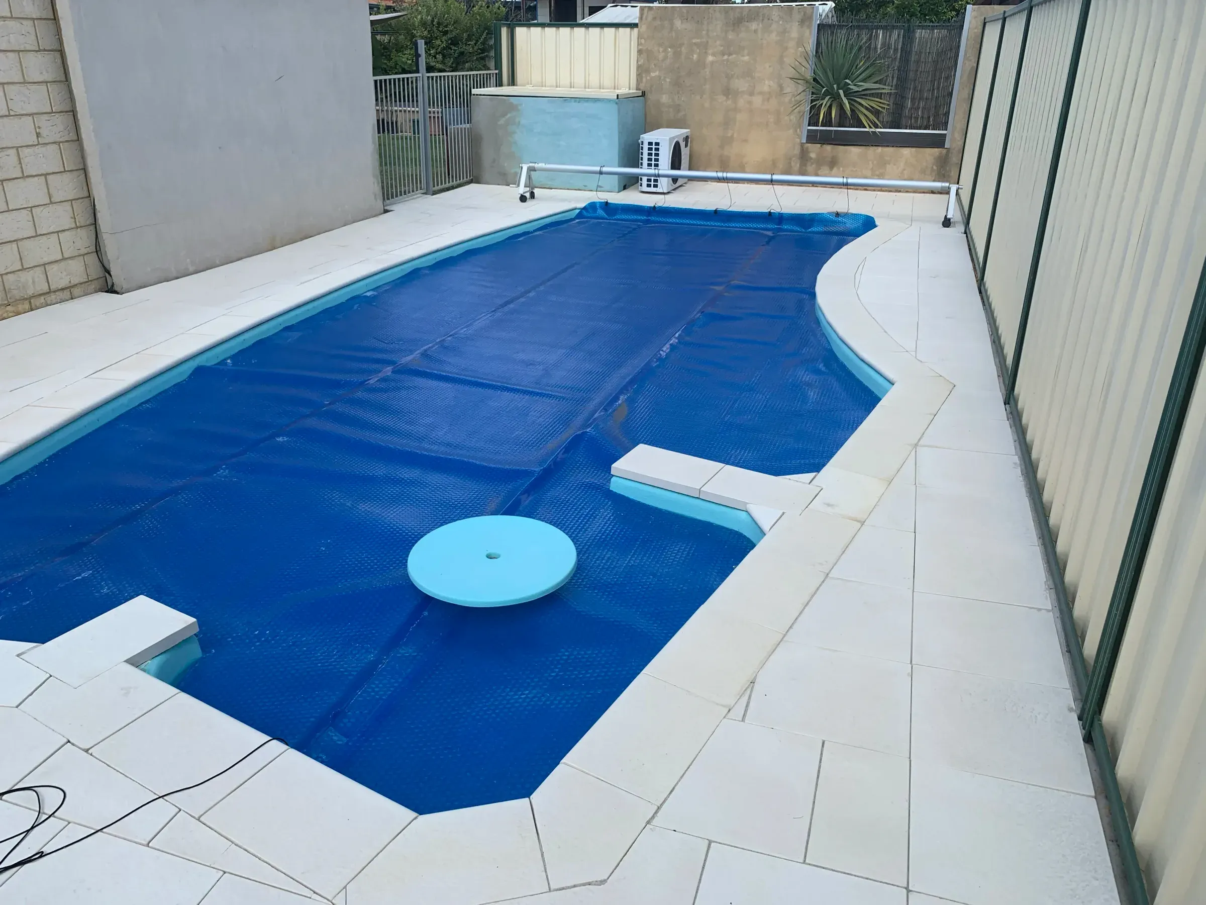 Completed pale paved pool surround running the full length of a covered pool
