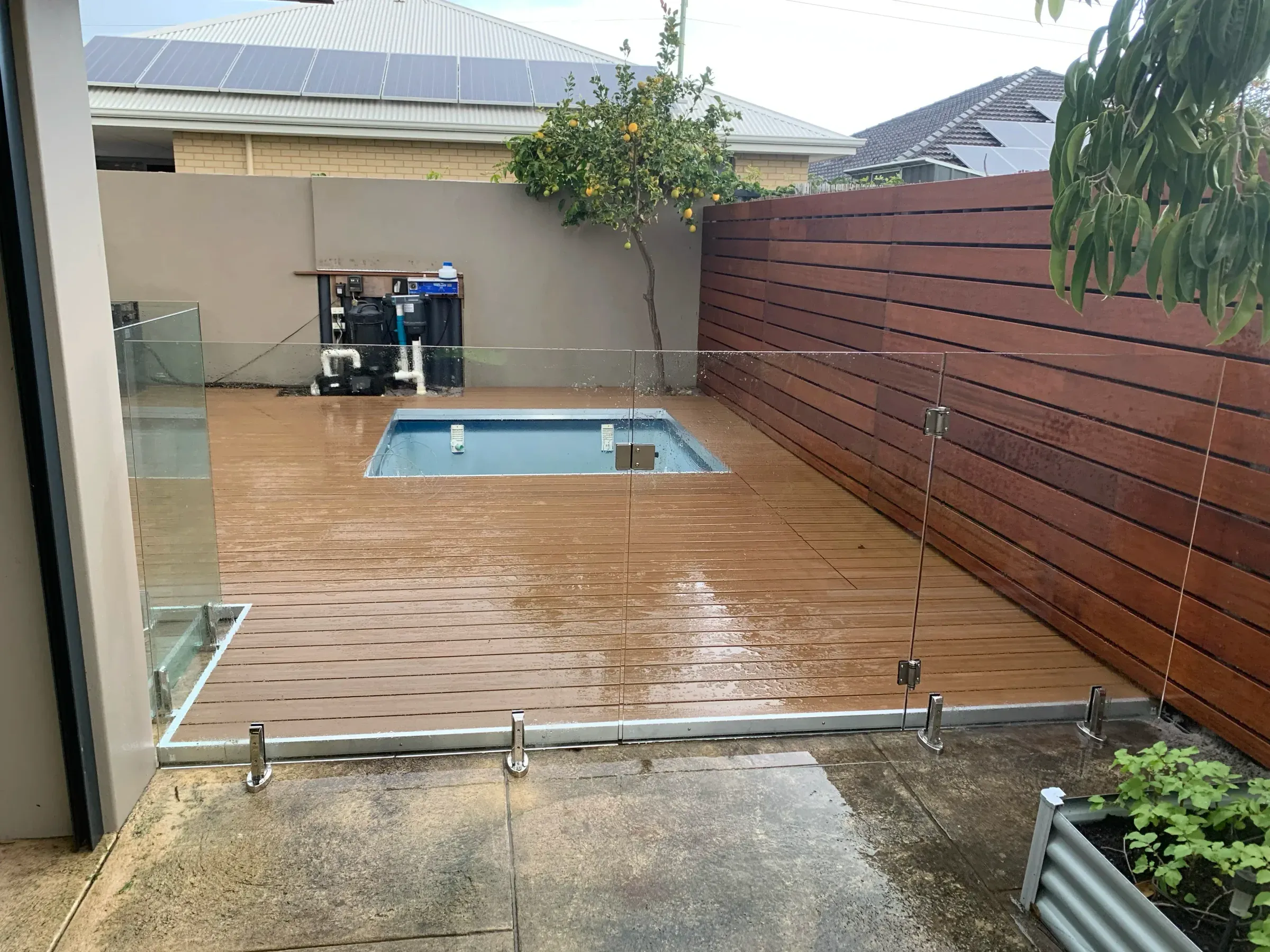 Frameless glass pool fence around a plunge pool set into a timber deck