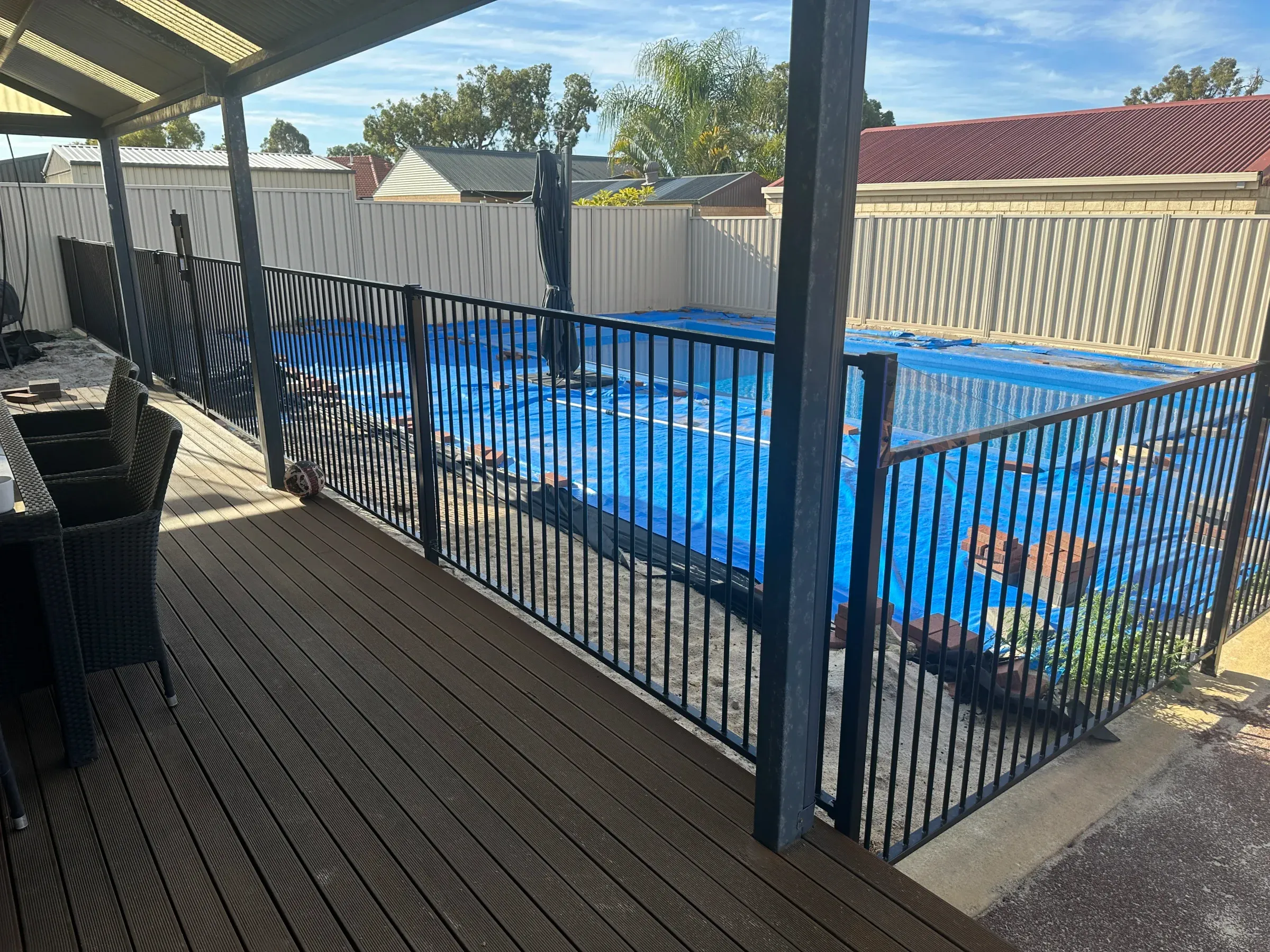 Black tubular pool fence viewed from a timber deck overlooking the pool