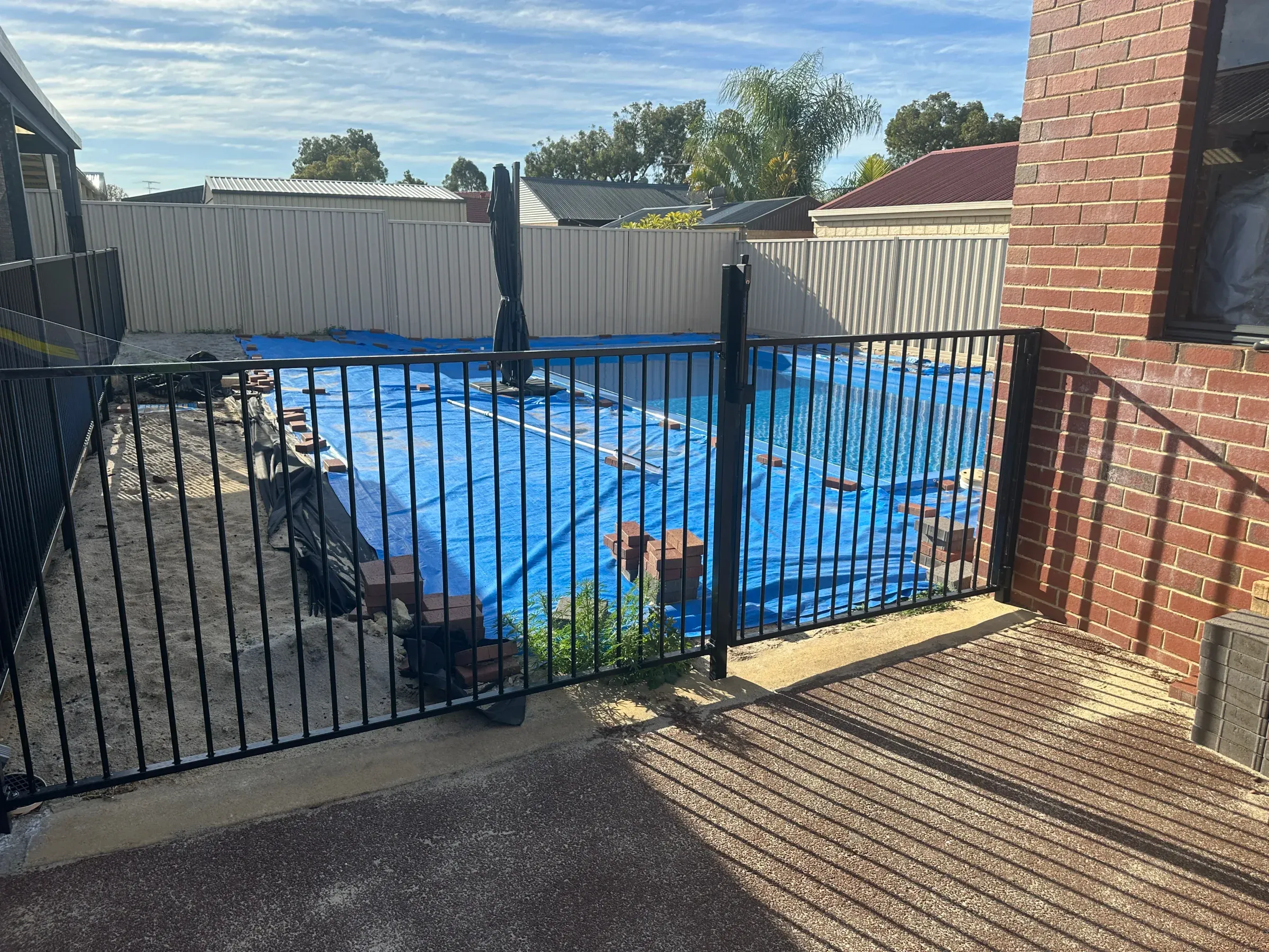 Black tubular pool fence running along the edge of a covered pool