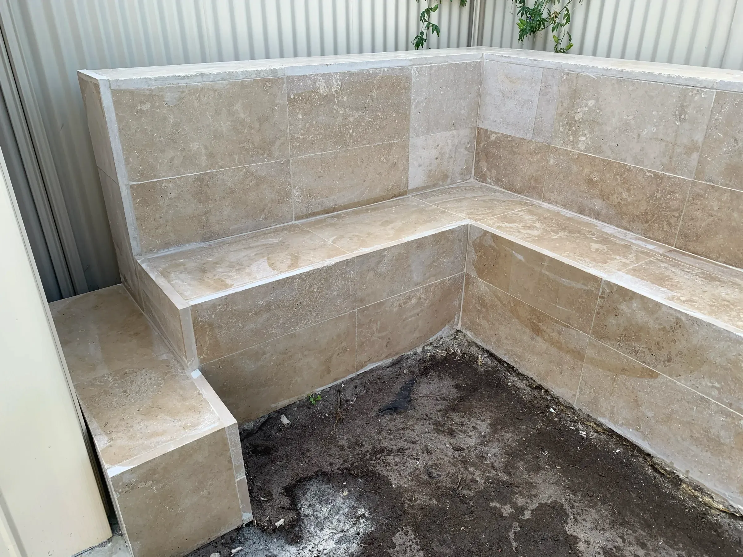 Tiled retaining wall returning at a corner to form a built-in bench seat