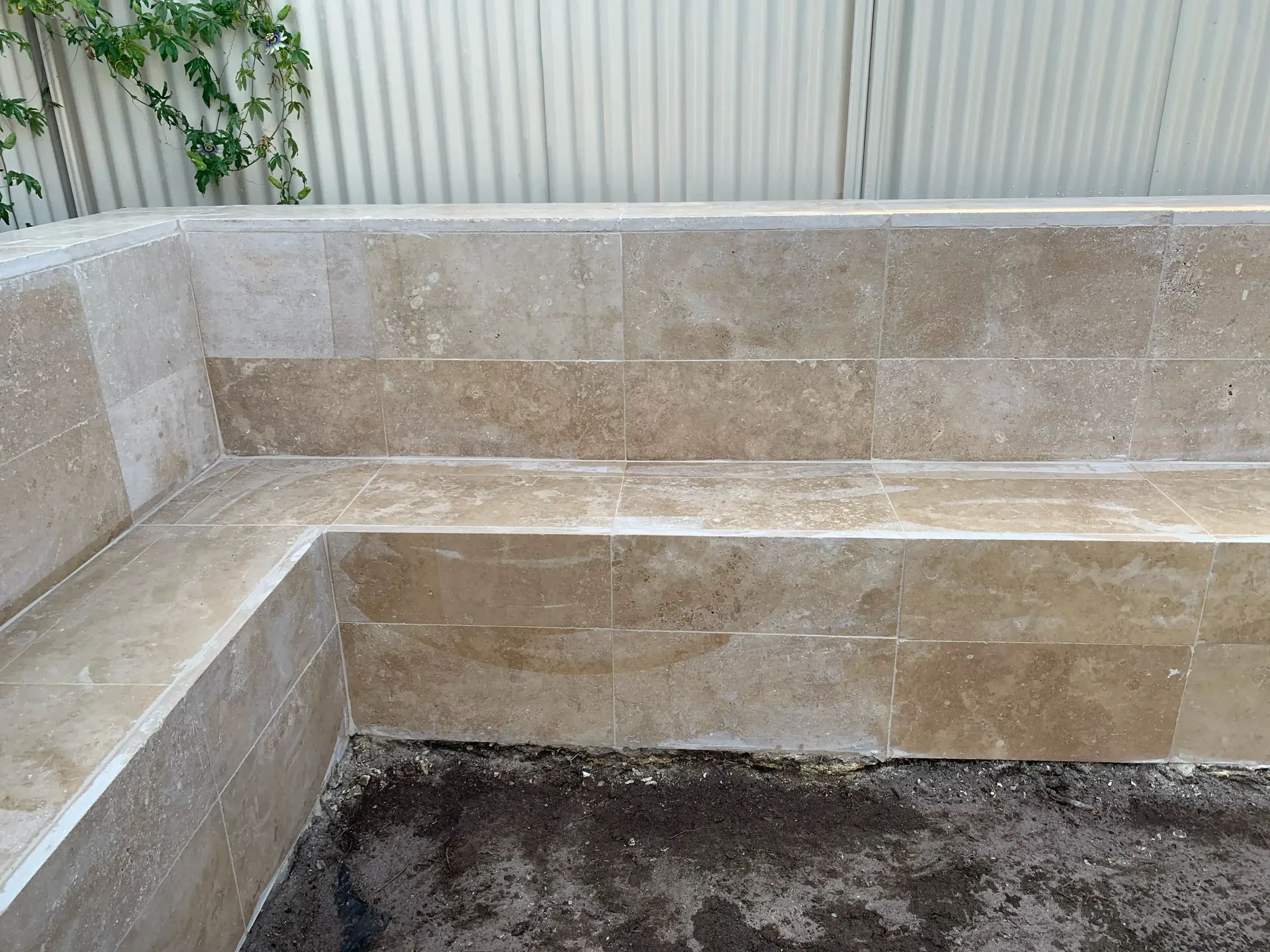 Tiled retaining wall and bench seat running along a boundary fence