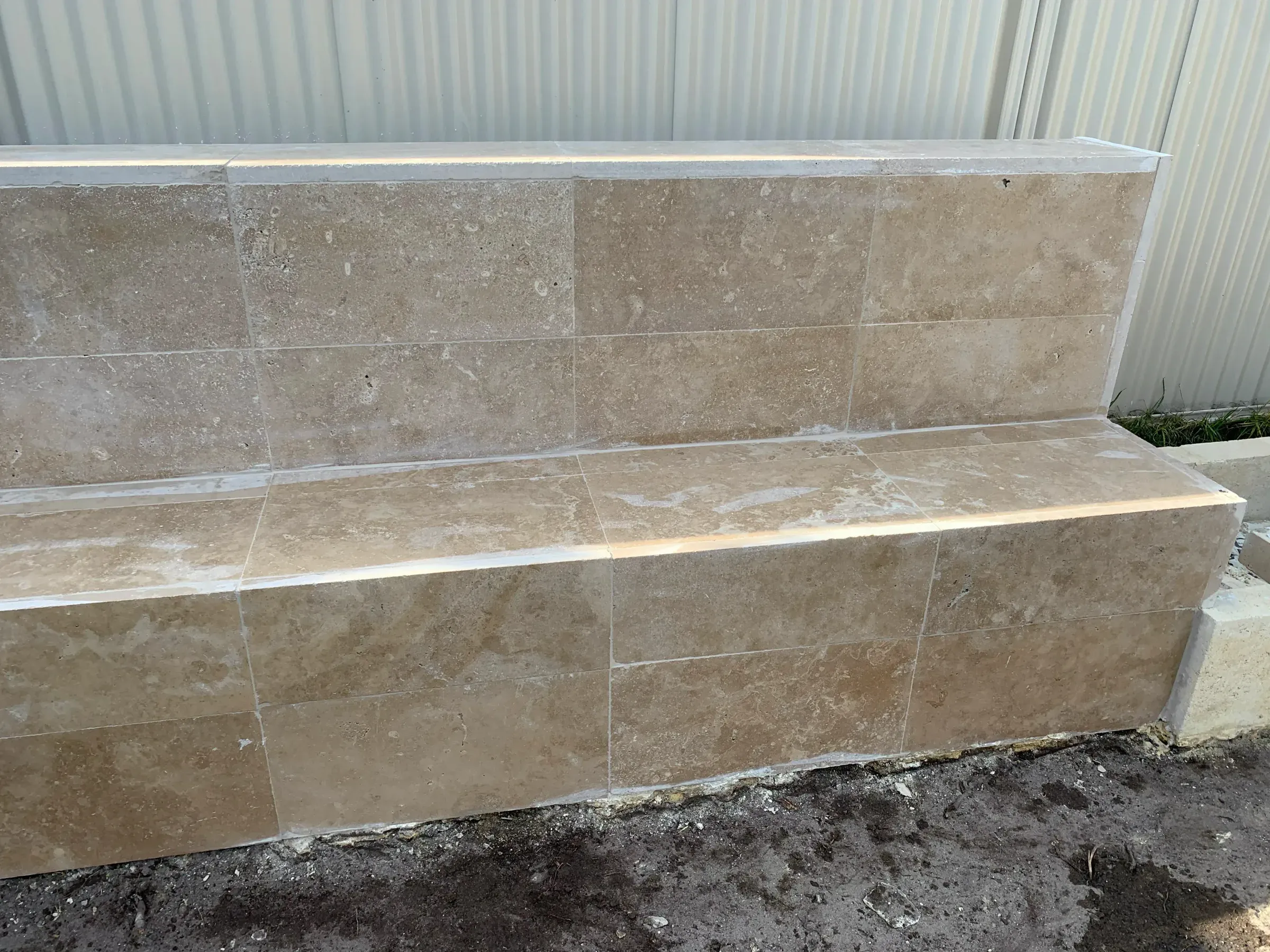 Wide view of a tiled retaining wall with a capped bench seat before the bed is filled