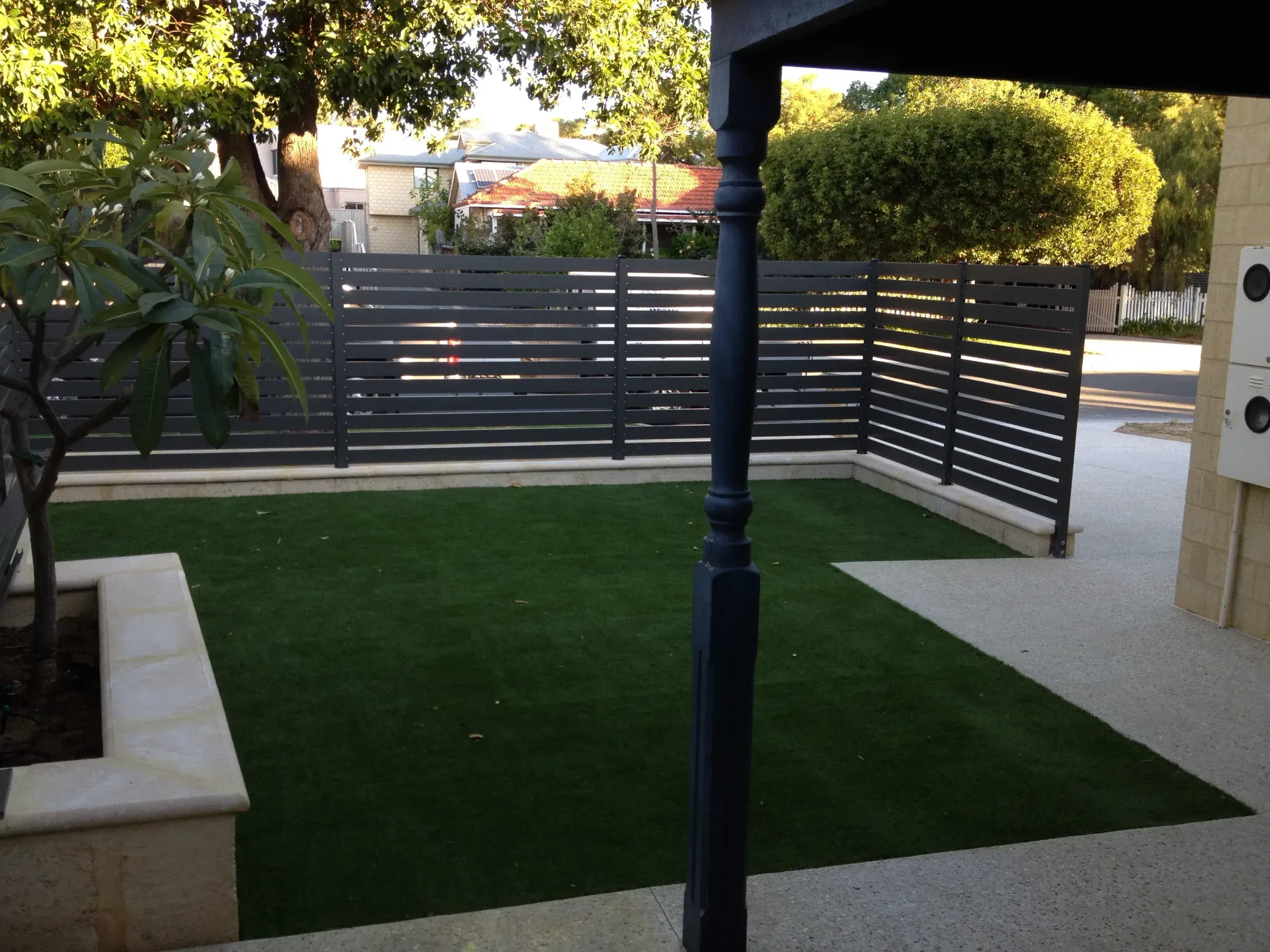 Synthetic turf laid in a small courtyard between an alfresco and a slat screen