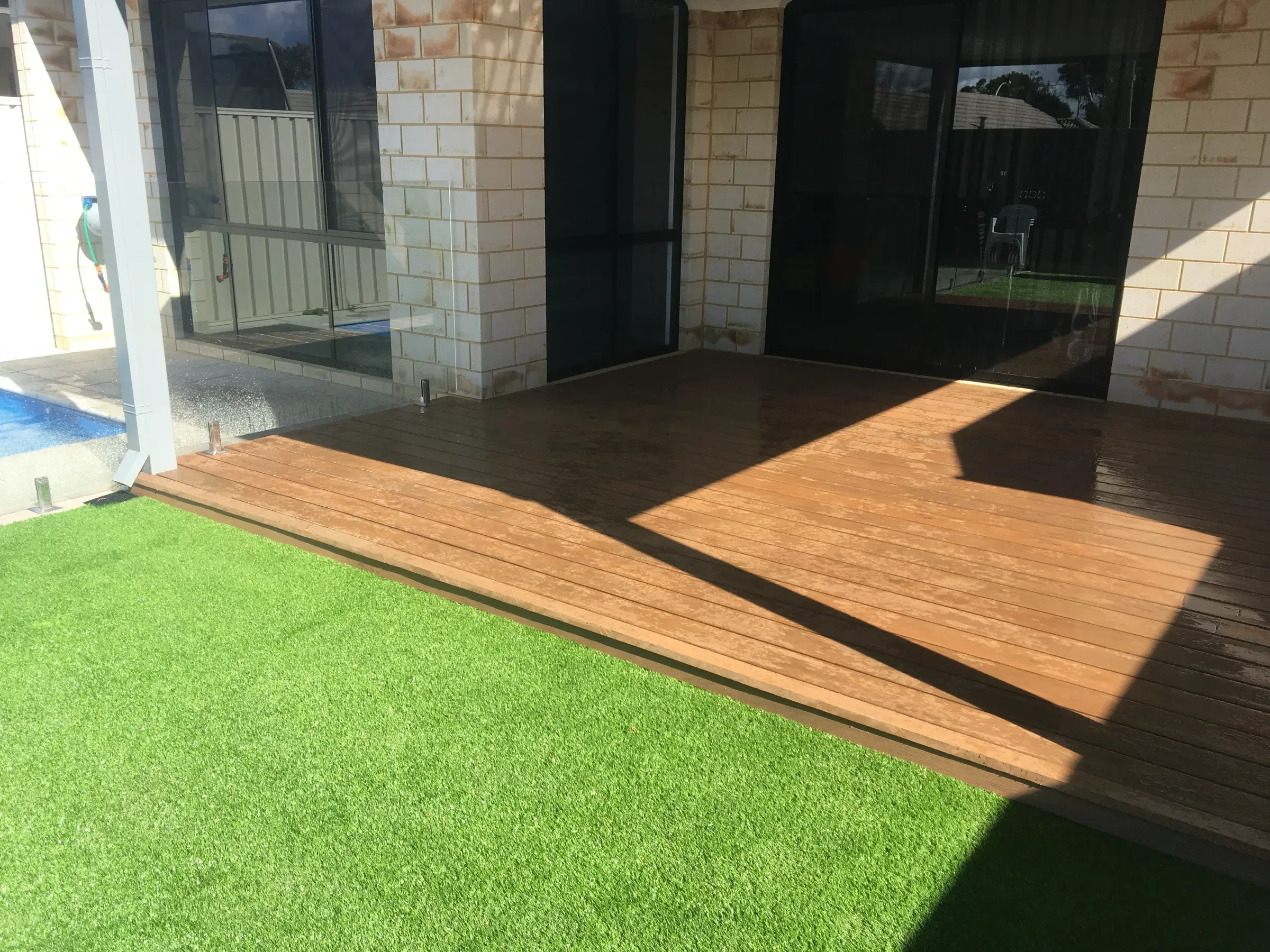 Synthetic turf meeting a jarrah deck at a flush threshold