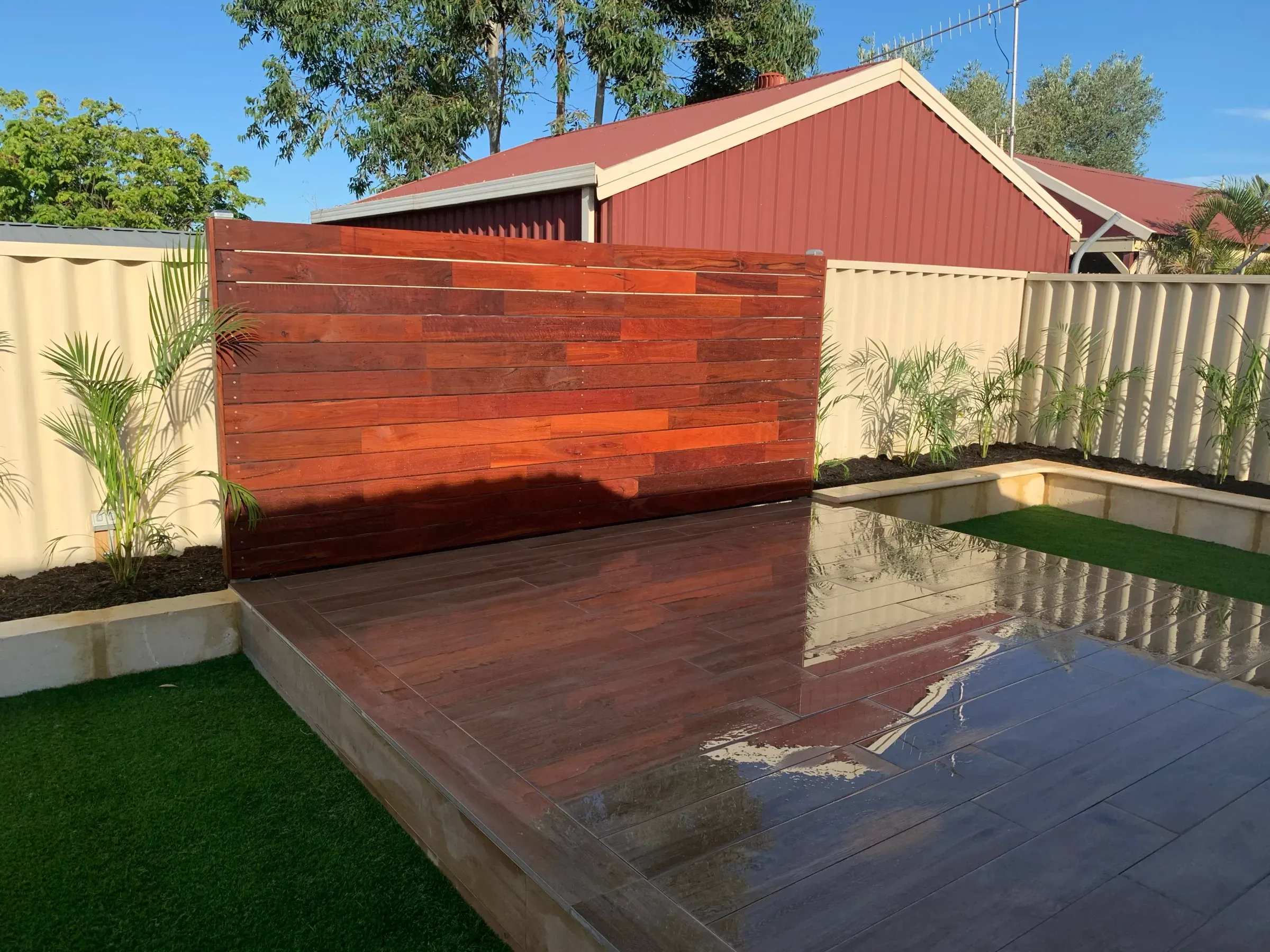 Jarrah deck and matching timber screen beside the pool in the same backyard
